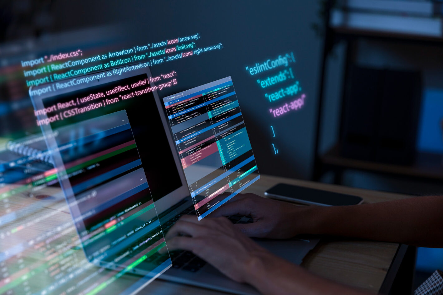 A person typing on a laptop with colorful lines of code on the screen in a dark setting.